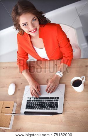 Attractive woman sitting at desk in office, working with laptop