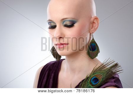 Portrait of beautiful hairless woman using peacock plumes as accessory.