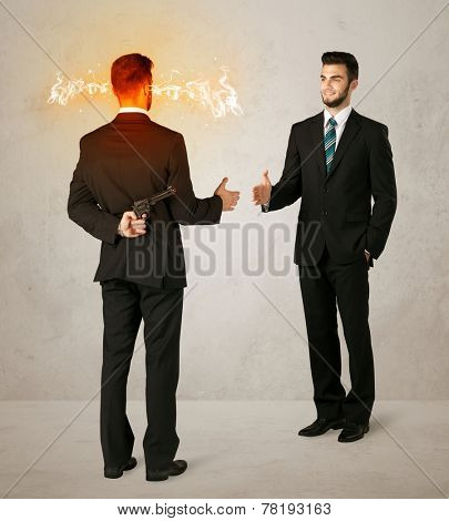Angry businessman hiding a weapon behind his back 