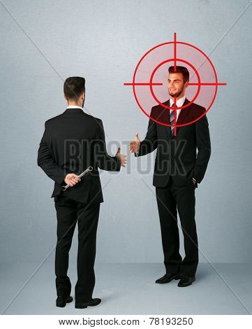 Ruthless businessman handshake with a hiding weapon and a head target point 