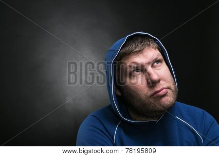 Adult man in the hood sits thinking