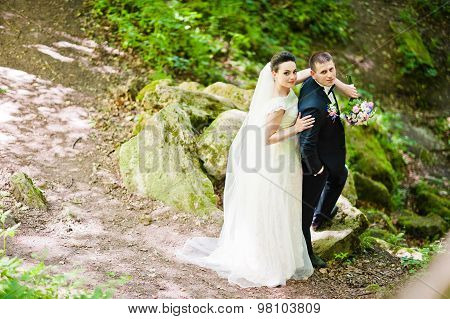 Gorgeus Wedding Couple On Green Sunny Forest On Stones