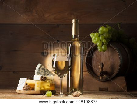 White wine with various types of cheese on wooden background
