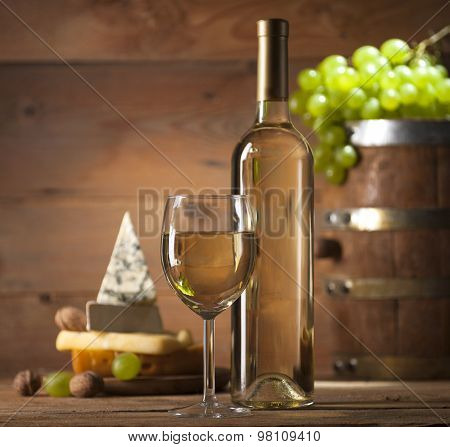 White wine with various types of cheese on wooden background