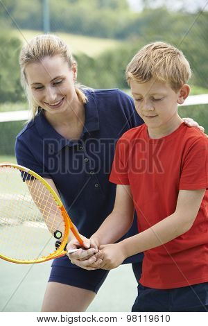 Female Tennis Coach Giving Lesson To Boy