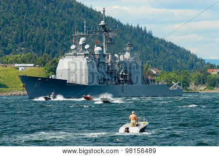 People in motorboats follow norwegian military ship in a fjord in Frogn, Norway.