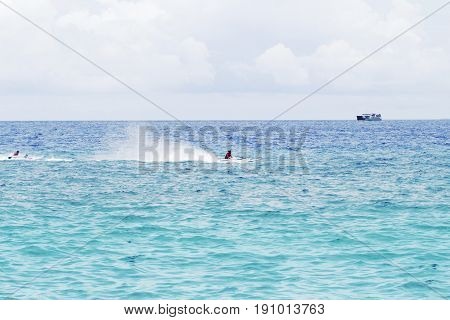 Seawater landscape with cargo ship on horizon and speedboat. Sea view of boats and sailors. Motor boats race in sea. Marine racing championship. High speed motorboat sail. Sea water spray. Water sport
