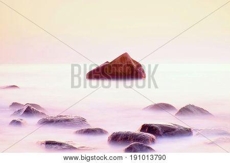 Romantic Morning At Sea. Big Boulders Sticking Out From Smooth Water Level. Pink Horozon With First