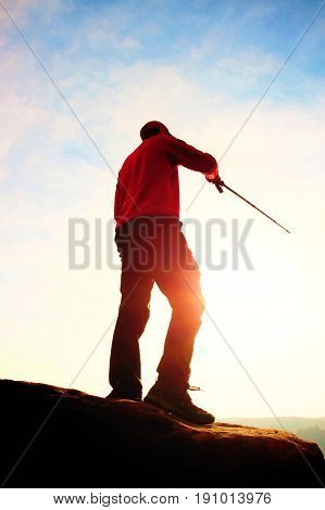 Tourist In Windcheater With Sporty Trecking  Poles In Hands Stand On Rocky View Point. Spring Commin