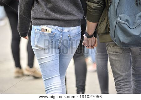 Shop Street Galway Ireland june 2017 Girl walking holding hans with boyfriends with the smartphone in the back pocket