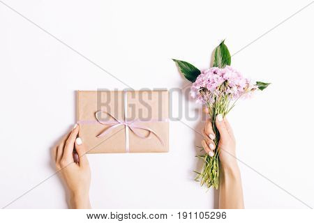 Small Bouquet Of Pink Carnations And Gift With Ribbon In Female Hands With Nail Polish