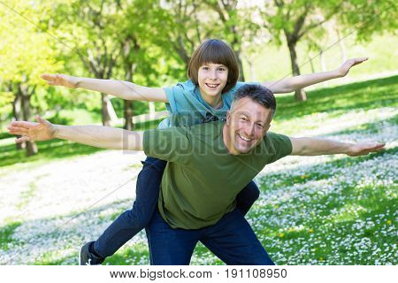 Portrait of father with his son having fun in summer park. Piggyback. Family fun. Happy boy playing with dad summer nature outdoor