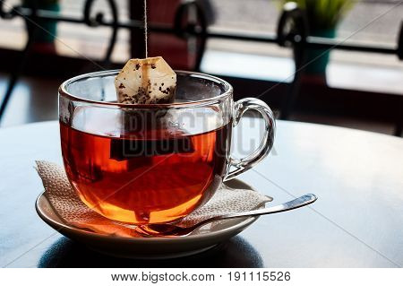 Closeup teabag put in water in teacup on saucer