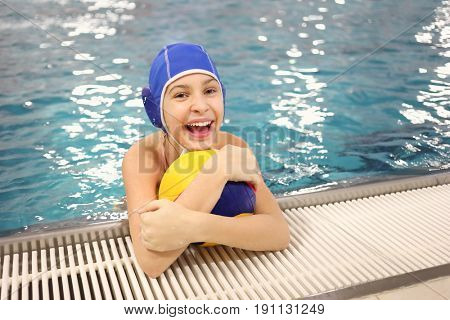 MOSCOW - NOV 17, 2016: Portrait of a happy young girl (with model releases) in an embrace with a ball for water polo in the pool