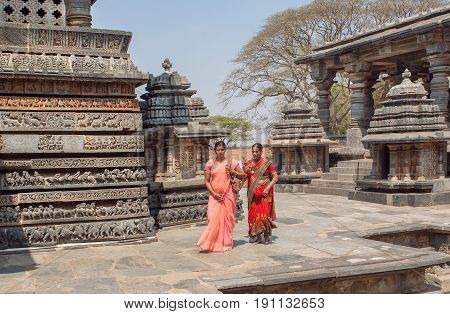 HALEBIDU, INDIA - FEB 22, 2017: Women in traditional indian sari going to ancient Hindu temple Hoysaleshwara with murble carvings on February 22, 2017. Temple built in 12th century dedicated to Shiva