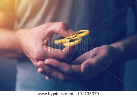 Yellow fidget spinner in male hand selective focus