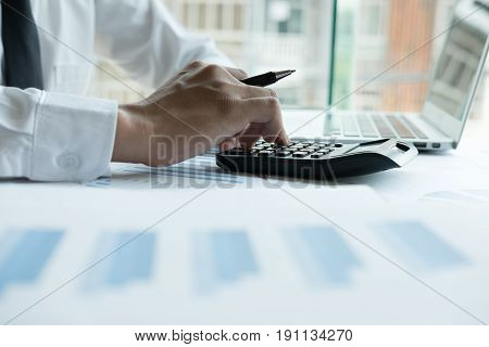 Young Businessman Working With Calculator, Business Document And Laptop Computer Notebook In Office.