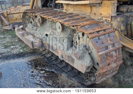 Continuous caterpillar tracks of the bulldozer. Old abandoned yellow bulldozer. Old rusty and weathered bulldozers