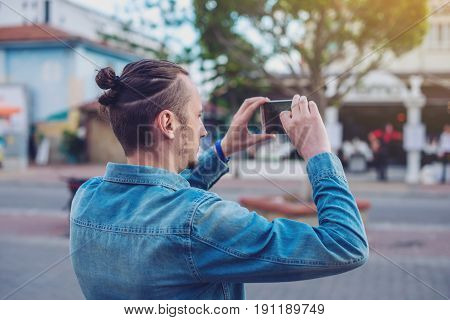 Man Backpack Makes A Photo On Your Smartphone On A City Street