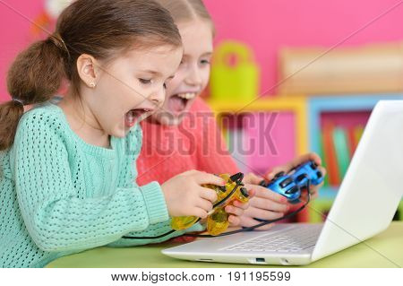 Two excited girls playing game on laptop