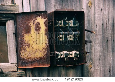 Old broken switchboard On a wooden wall . Broken disassembled plundered electrical switchboard. Broken old shield control panel of equipment operation. Industrial trash