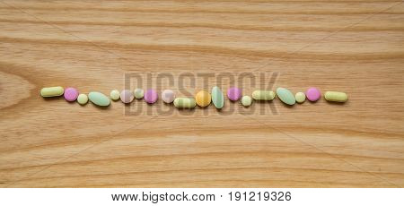 Lot Of Colorful Pills On A Wooden Table