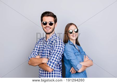 Two Cheerful Young Lovers Are Looking In The Camera, Wearing Stylish Sunglasses And Smile, In Casual