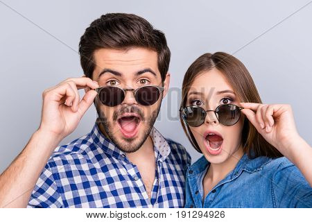 Really?! Two young shocked lovers are amazed with wide open eyes mouthes fixing in a casual wear on light background