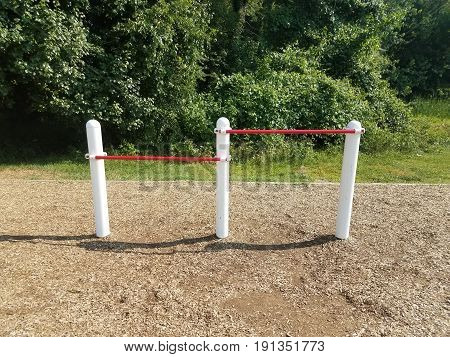 white and red metal bars on playground with wood chips