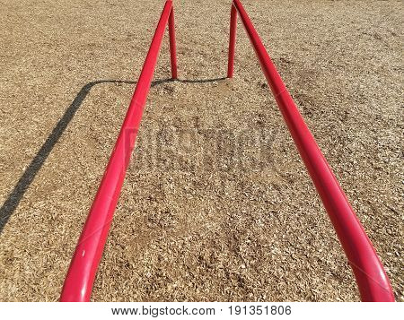 horizontal red metal bars on playground with wood chops