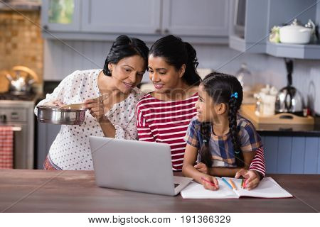 Multi-generation family using laptop in kitchen at home