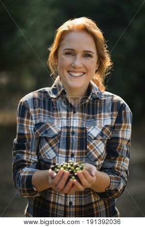 Portrait of smiling female holding olives at farm