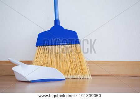 Close-up of dustpan and sweeping broom on wooden floor