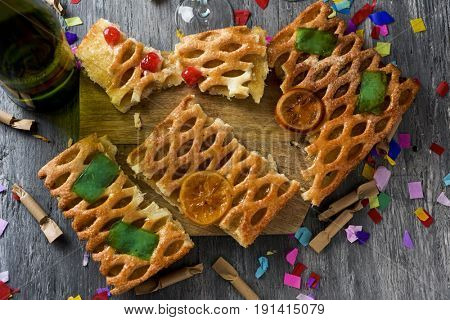 high-angle shot of a coca de Sant Joan, a typical sweet flat cake from Catalonia, Spain, eaten on Saint Johns Eve, a bottle of champagne, firecrackers and confetti on a rustic table