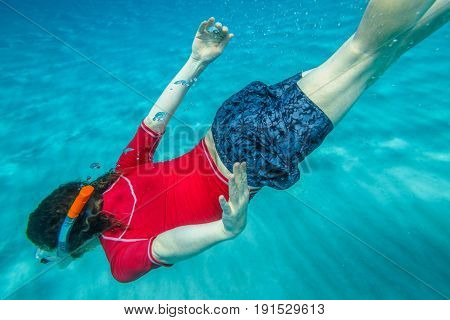 Male apnea swims in crystal sea. Underwater background of a man snorkeling and doing free diving. Watersport activity in summer vacations. Tropical destination holidays concept.