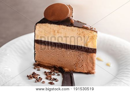 Delicious vanilla ice cream cake, coffee and three layer chocolate, served with chocolate chips covered by a layer of chocolate on a white rectangular plate, on wooden table background.