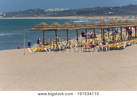 ALVOR, PORTUGAL - APRIL 23, 2017: People at the famous beach of Praia do Alvor, Algarve region, Portugal