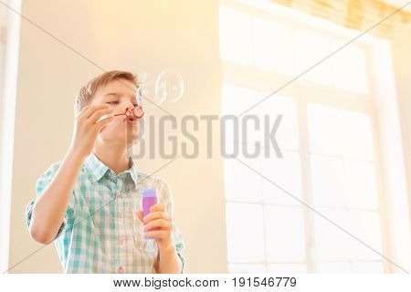 Boy blowing bubbles at home