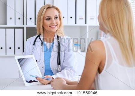 Doctor and  patient  discussing something while phisician pointing into laptop computer. Medicine and health care concept