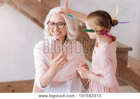 Time for selfie. Happy delighted aged woman smiling and posing for a photo while taking a selfie