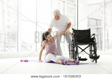 Young disabled woman with senior orthopedist in rehabilitation clinic
