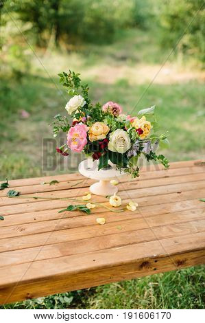 floral design, wedding, romance concept - gorgeous bouquet made of tender avalanches, roses, peonies and dianthuses, decorated with leaves of oak and raspberry-bush, standing in vase on wooden table