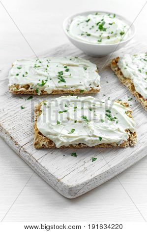 Homemade Crispbread toast with Cream Cheese and parsley on white wooden board background