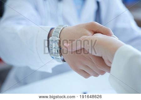 Male doctor shaking hands with patient. Partnership trust and medical ethics concept. Handshake with satisfied client. Thankful handclasp for excellent treatment.