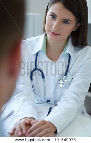 Friendly female doctor's hands holding male patient's hand for encouragement and empathy. Partnership trust and medical ethics concept. Bad news lessening and support.