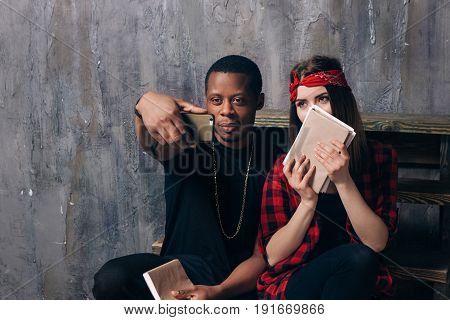 Interracial classmates couple taking selfie on phone. Black guy and white girl are studying together. Students have fun