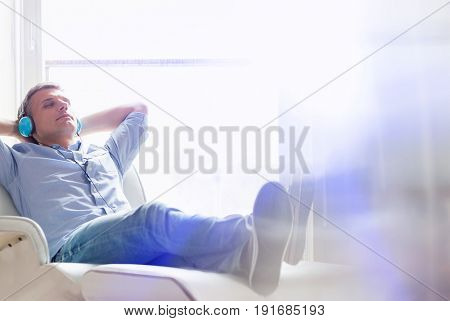 Full-length of relaxed Middle-aged man listening to music at home