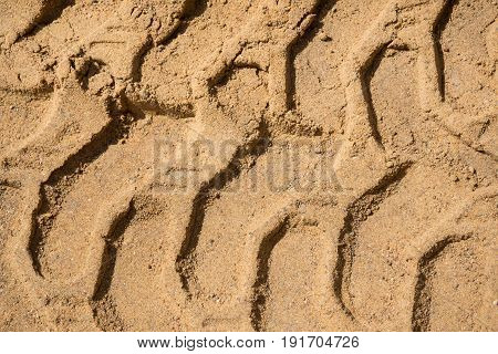 Trace of the tractor on the sand. The background of the industrial sand for construction works. Natural material for bricks and concrete products - on-site production work.