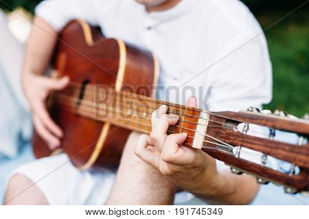 man plays guitar. wide andle. guitar neck and playing fingers foreground