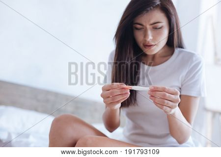 Something must be wrong. Young woman looking confused while viewing a control line on a pregnancy test.